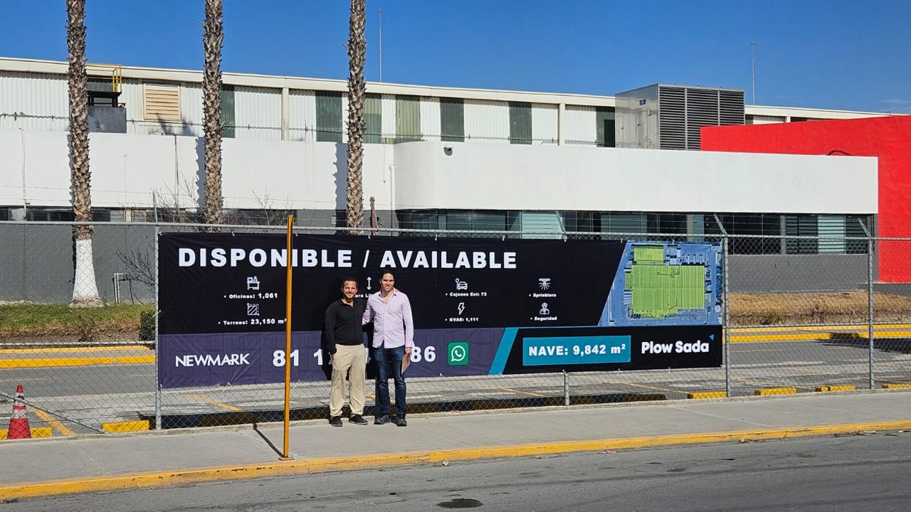 Industrial warehouse behind an availability banner, with two men standing in front.