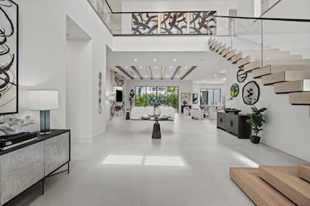 Double-height living room with a floating staircase, glass railing, and contemporary furnishings.