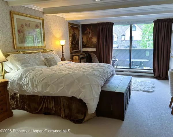 Furnished bedroom with a large bed and sliding glass doors leading to a balcony.