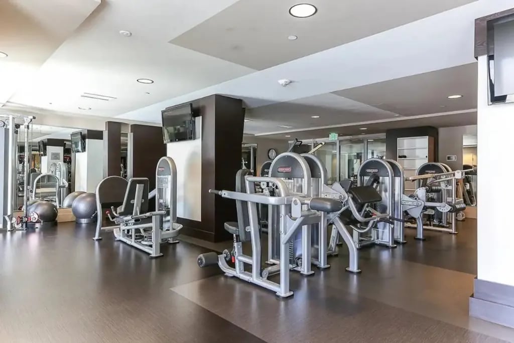 An expansive fitness center at the Madrone with various modern gym equipment and machines for resident use.