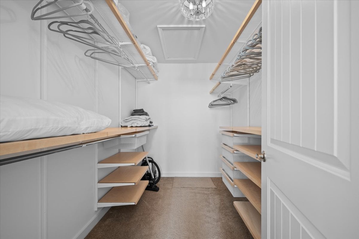 Walk-in closet with built-in wood-topped shelves, overhead hanging rods, folded linens, and a partially visible wheelchair.