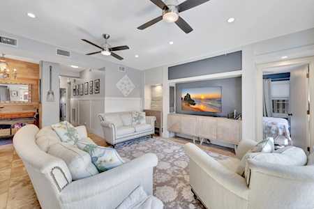Furnished living room with white seating, two ceiling fans, and a television above a console.