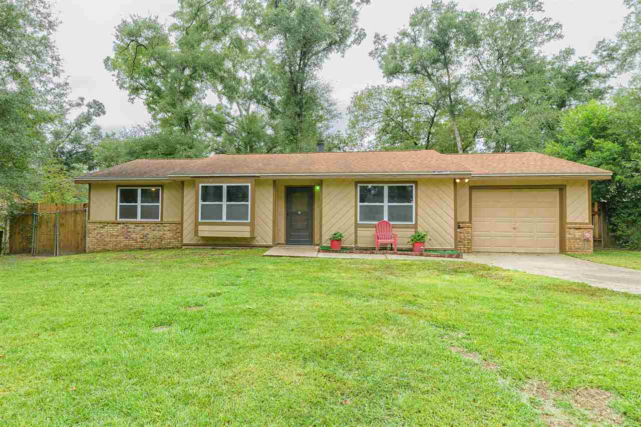 A spacious home featuring a large yard and an attached garage, surrounded by greenery and open space.