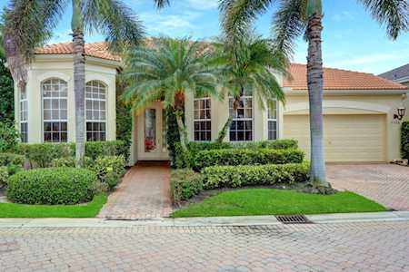 Single-story home with arched windows, palm trees, and a red tile roof.