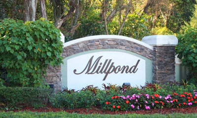 Millpond neighborhood entrance sign surrounded by flowers and greenery.