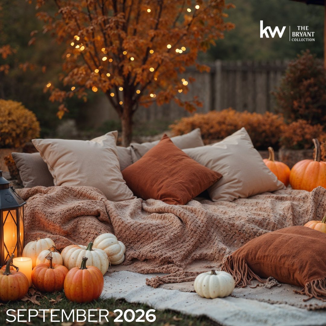Autumn patio seating with pumpkins, layered blankets, cushions, and glowing string lights.
