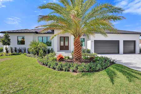 Modern single-story home with two garage doors and a palm tree in the front lawn.