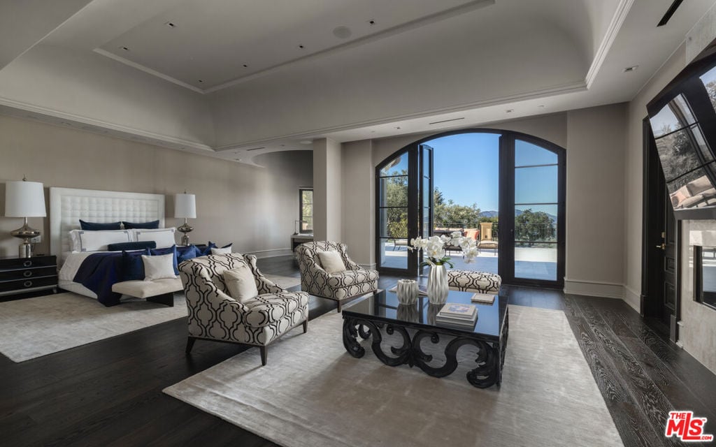 Staged bedroom suite with an upholstered bed and arched glass doors overlooking a pool.
