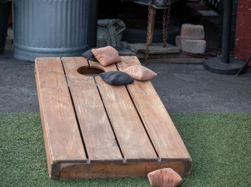 Wooden cornhole board and beanbags set out for an outdoor game.