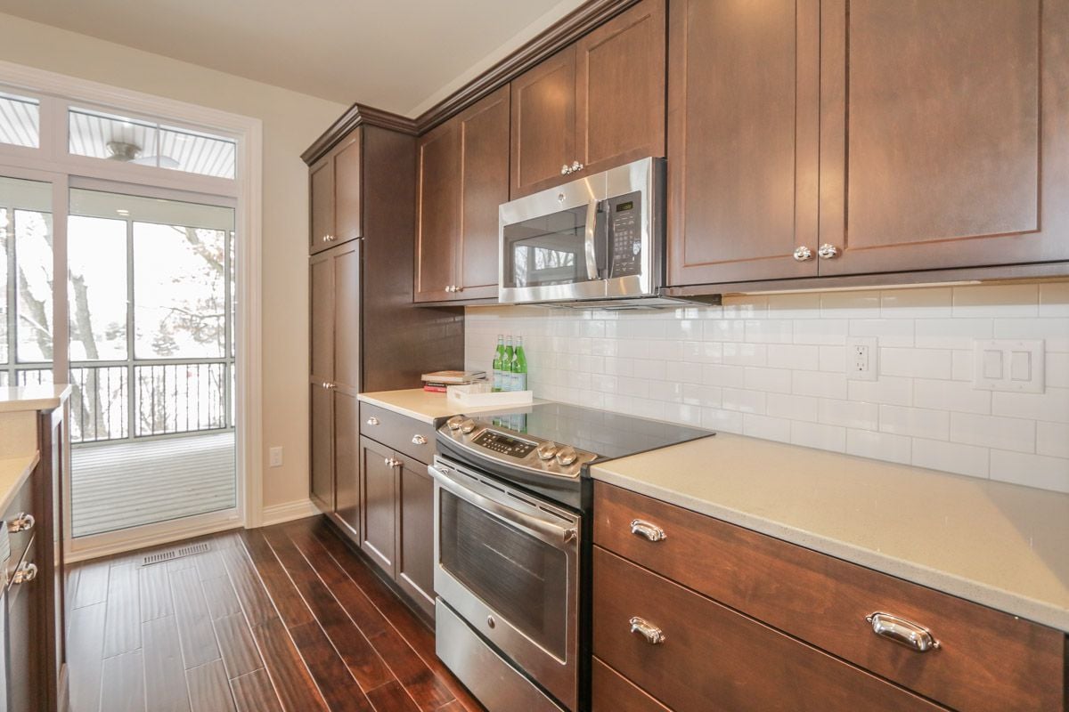 Kitchen with dark wood cabinets, stainless steel appliances, and a sliding glass door to a balcony.