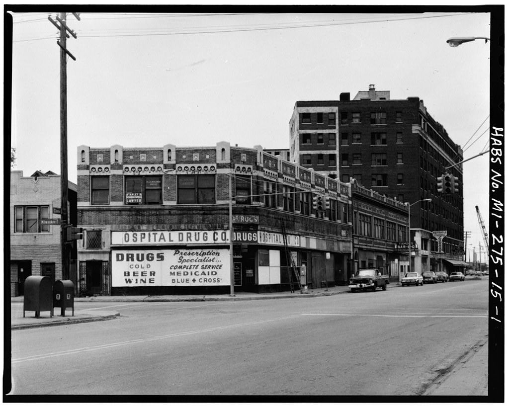 Detroit commercial street with a corner drugstore, brick storefronts and a tall adjoining building.