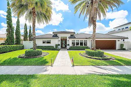 Modern single-story home with a central walkway, palm trees, and a wide brown garage door.