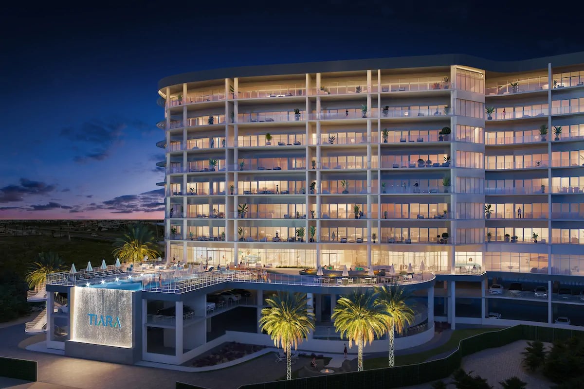 Tiara on the Beach condominium rendering at dusk, with illuminated balconies and an elevated pool.