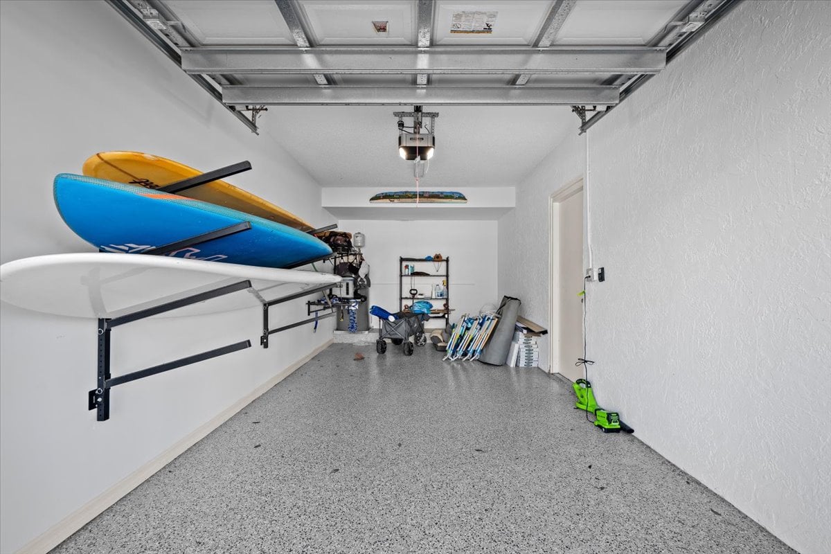 Garage with kayaks on wall racks and beach gear stored along the back wall.