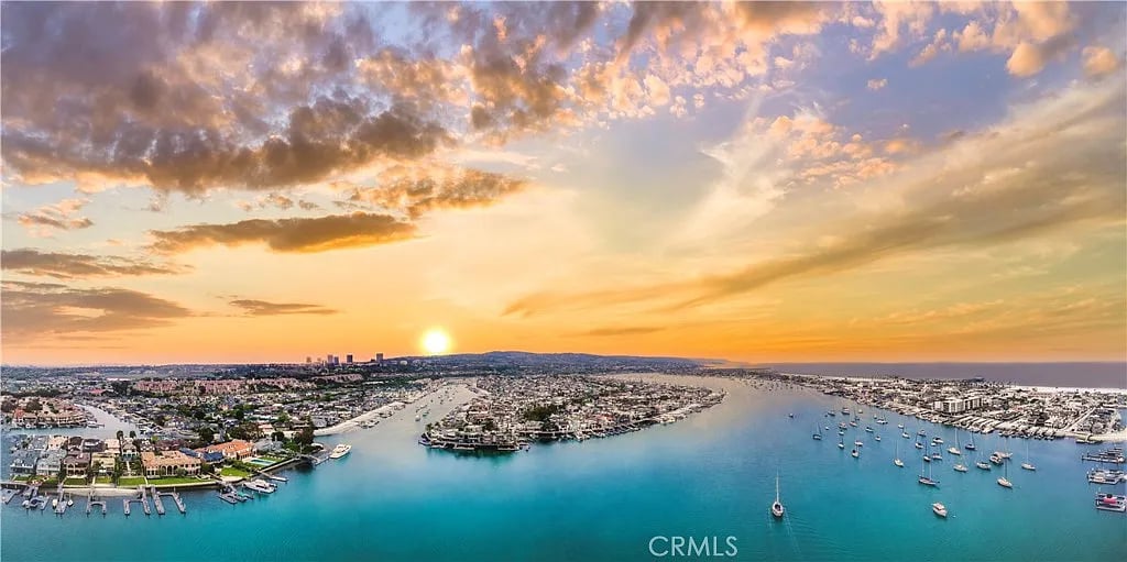 Aerial harbor view at sunset, with a marina full of boats and waterfront homes.