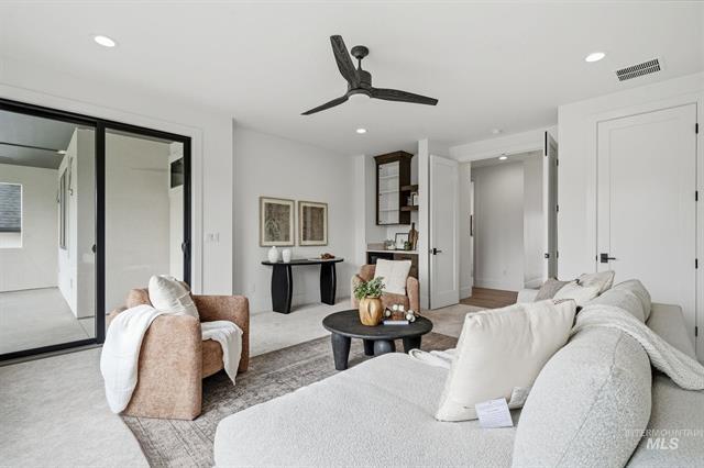 Modern living room with white sectional, blush chair, round black coffee table, and black-framed sliding doors.