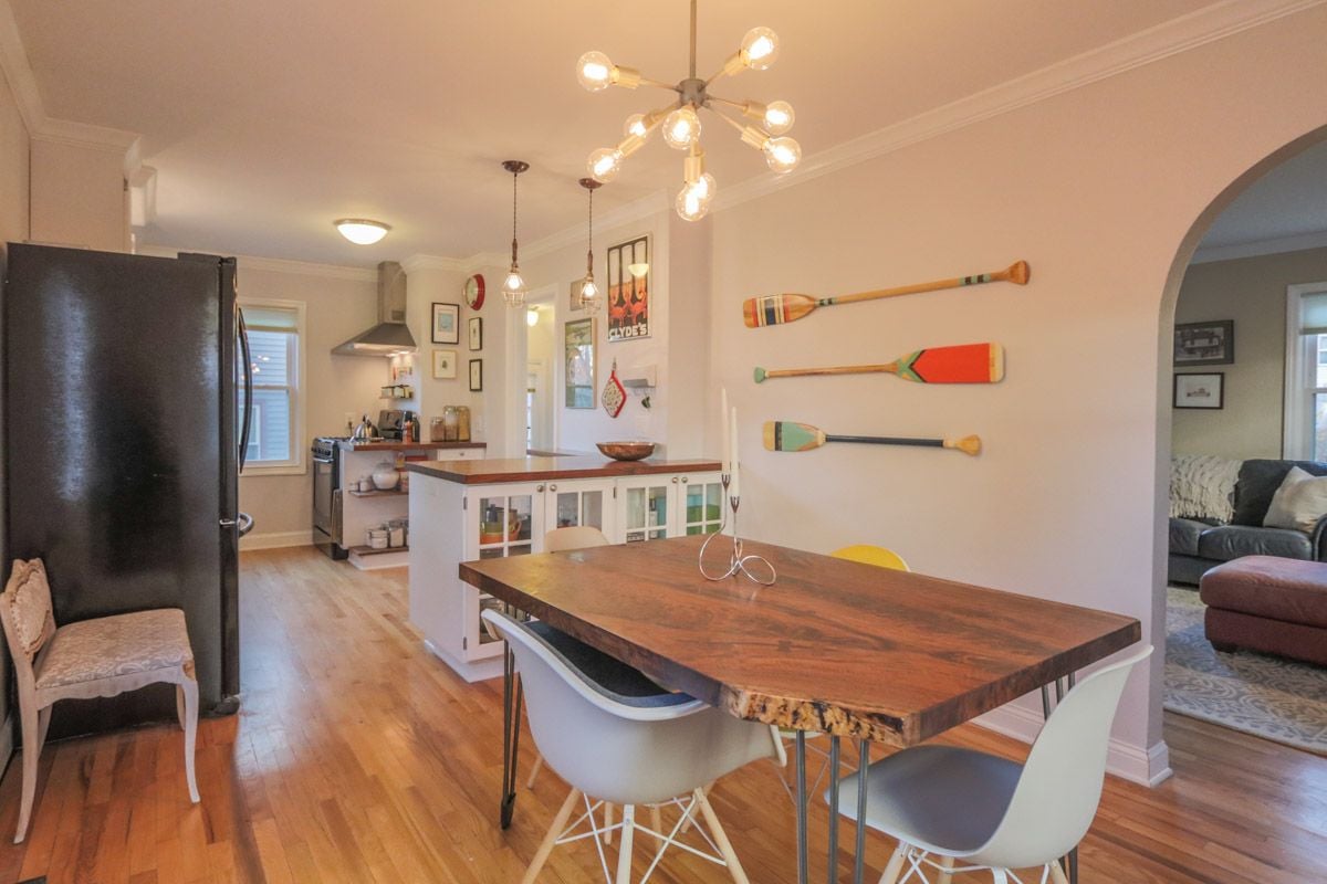 Open-plan kitchen and dining area with a large wood table and colorful oars on the wall.