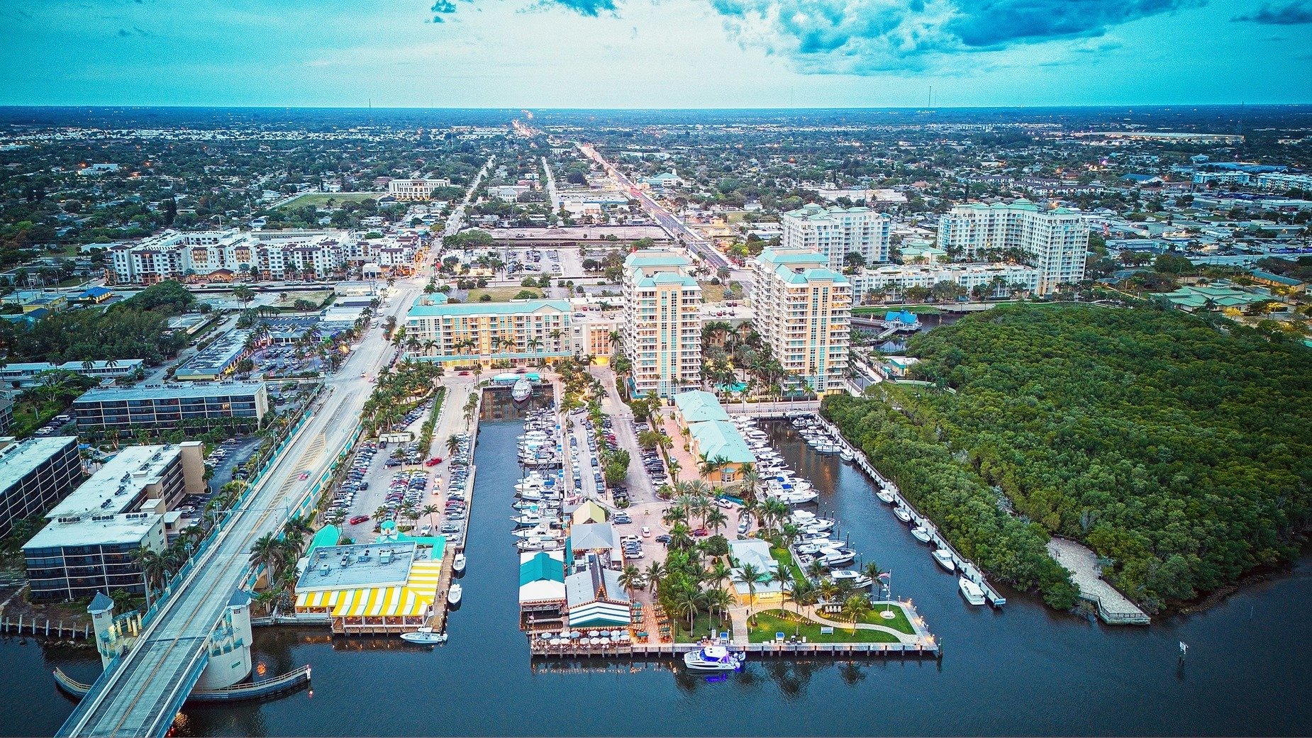 Aerial view of waterfront apartments and a marina beside a mangrove shoreline.