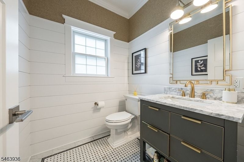 Bathroom with a dark double vanity, marble countertop, gold-framed mirror, and black-and-white tile floor.