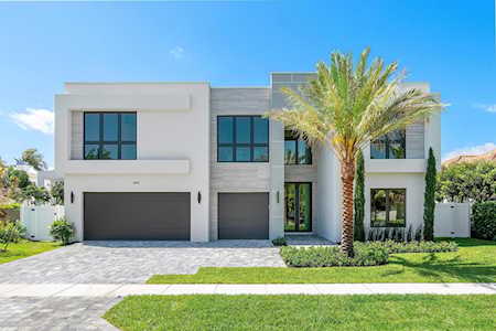 Modern two-story home with a broad driveway and palm tree in the front lawn.