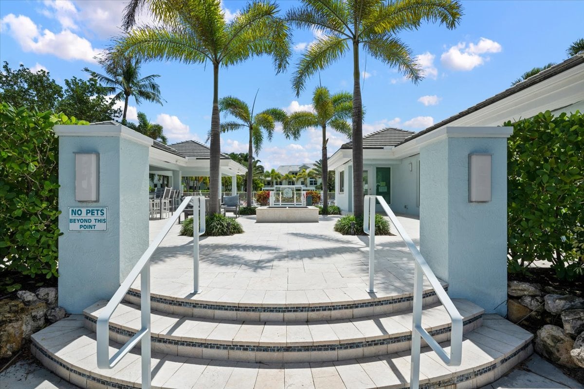 Sea Colony Condominium courtyard entrance with tiled steps, palm trees, and a no-pets sign.