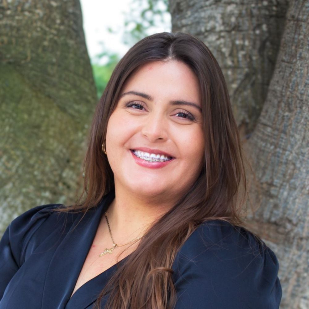 Adriana Vargas Mendoza smiling in a navy blazer outdoors.