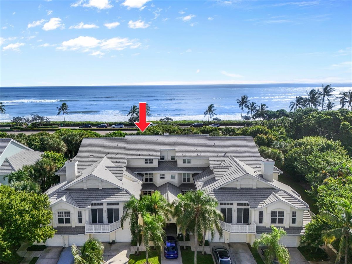 Sea Colony condominium beside the ocean, marked by a red arrow in an aerial view.