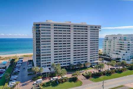 Beachfront condominium tower beside the Atlantic Ocean, with a neighboring high-rise and landscaped grounds.