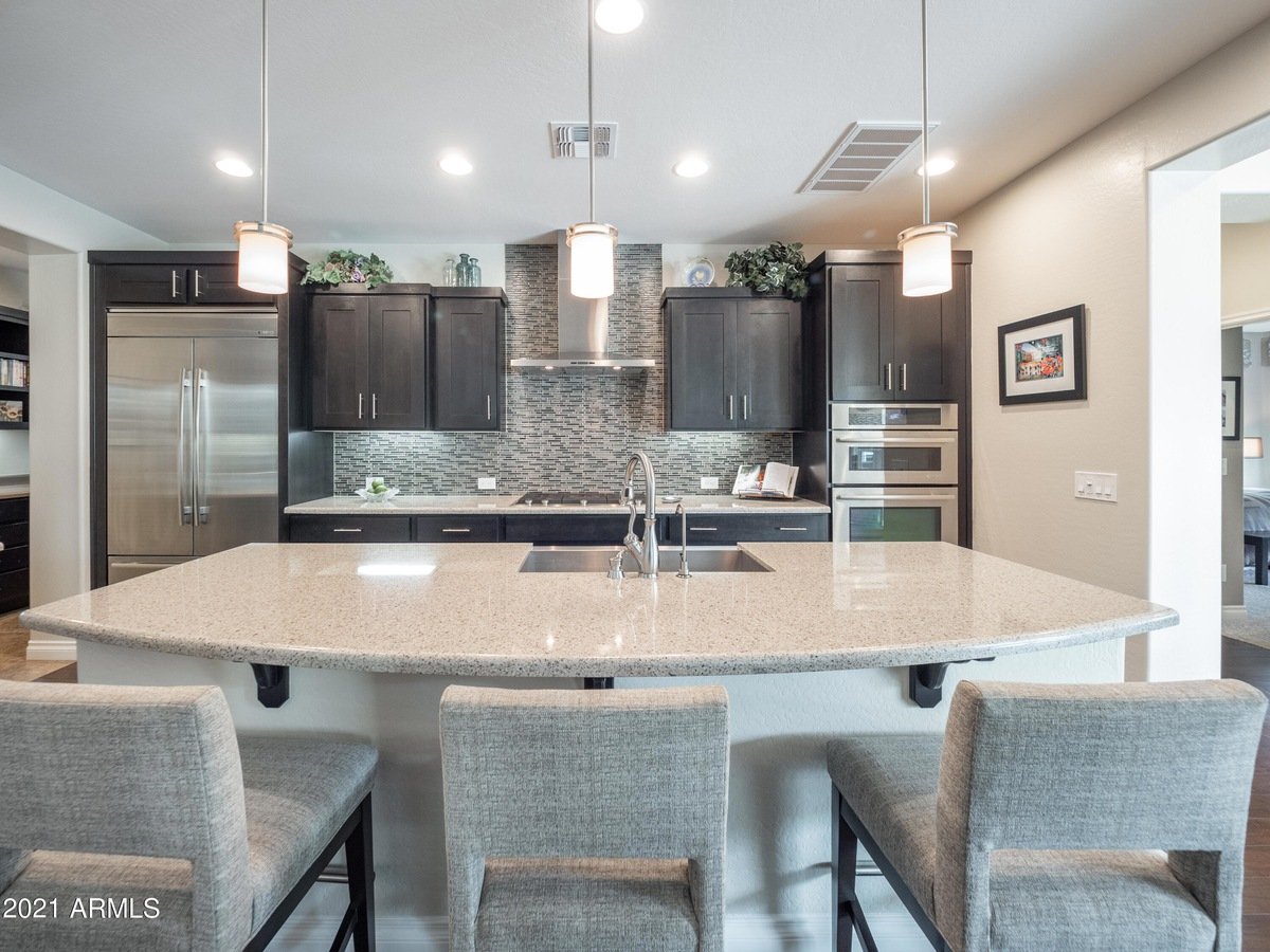 Modern kitchen with dark cabinets, stainless appliances, and a large stone island with bar seating.