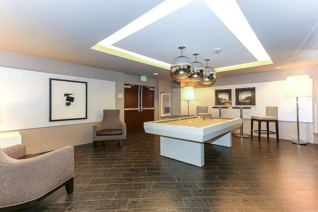 A recreation room at the Madrone, with a white-framed pool table and contemporary lighting, perfect for resident gatherings.