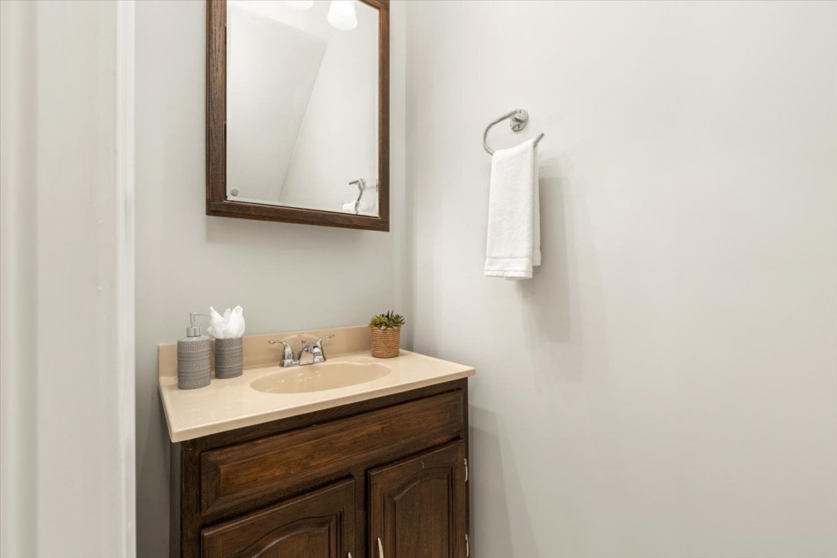 Bathroom vanity with a dark wood cabinet, beige sink countertop, and framed mirror.