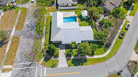 Aerial view of a corner-lot home with a light metal roof and backyard pool.