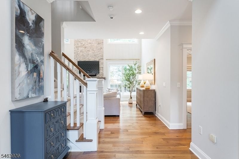 Entry hall with hardwood floors, a blue chest, and a staircase opening onto a bright living room.