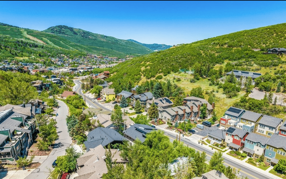 Aerie homes spread across a green hillside, with Park City and mountains in the distance.