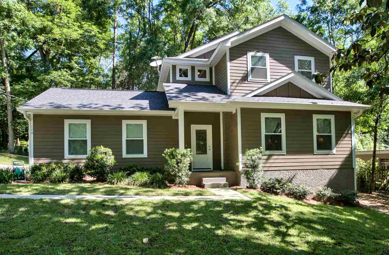 A cozy home featuring brown siding, surrounded by lush green grass in a serene outdoor setting.