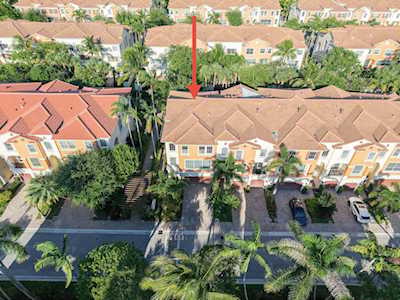 Aerial view of attached homes, with a red arrow pointing to a tan-roofed residence.