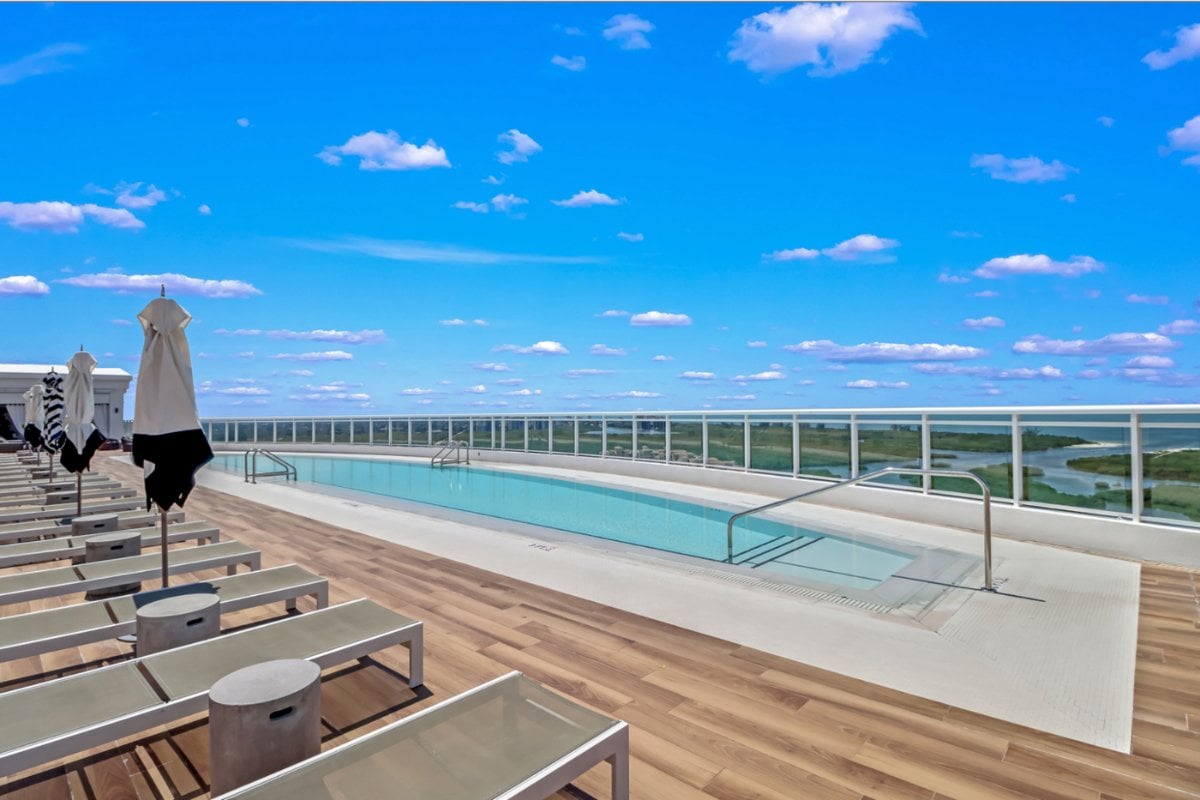 The rooftop infinity pool at Kalea Bay, with loungers and umbrellas along the deck and the mangrove estuary and Gulf beyond.