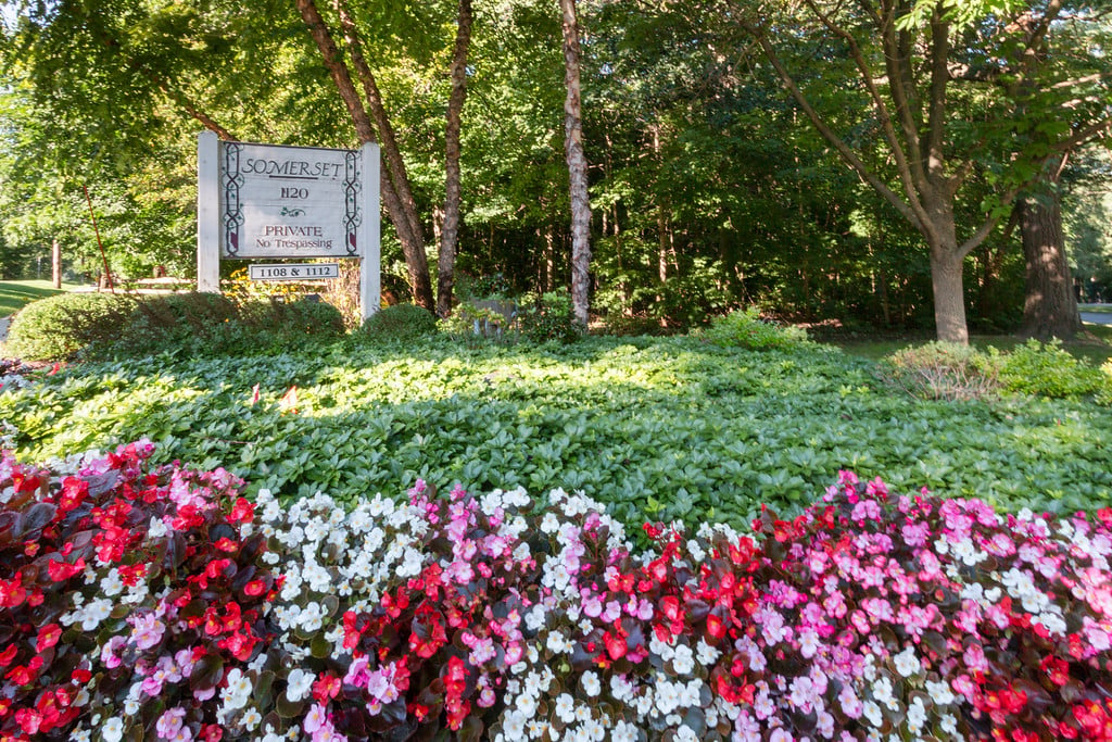 Somerset property sign among mature trees and colorful flower beds.