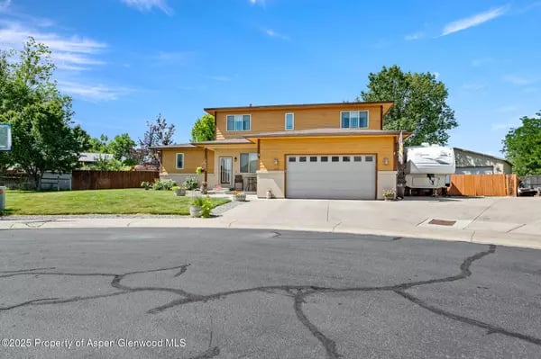 Two-story ochre home with an attached garage and an RV parked beside it.