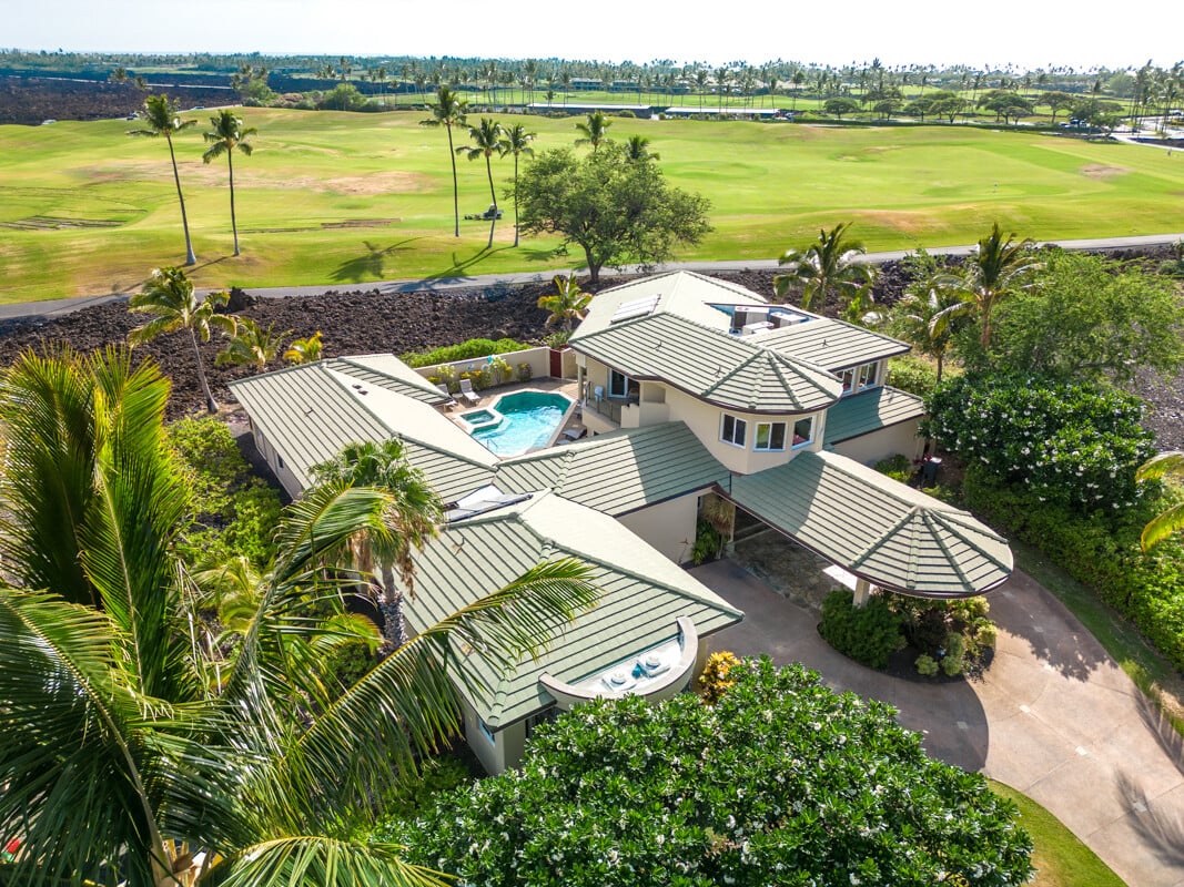 Aerial view of a sprawling home with a swimming pool beside a golf course.