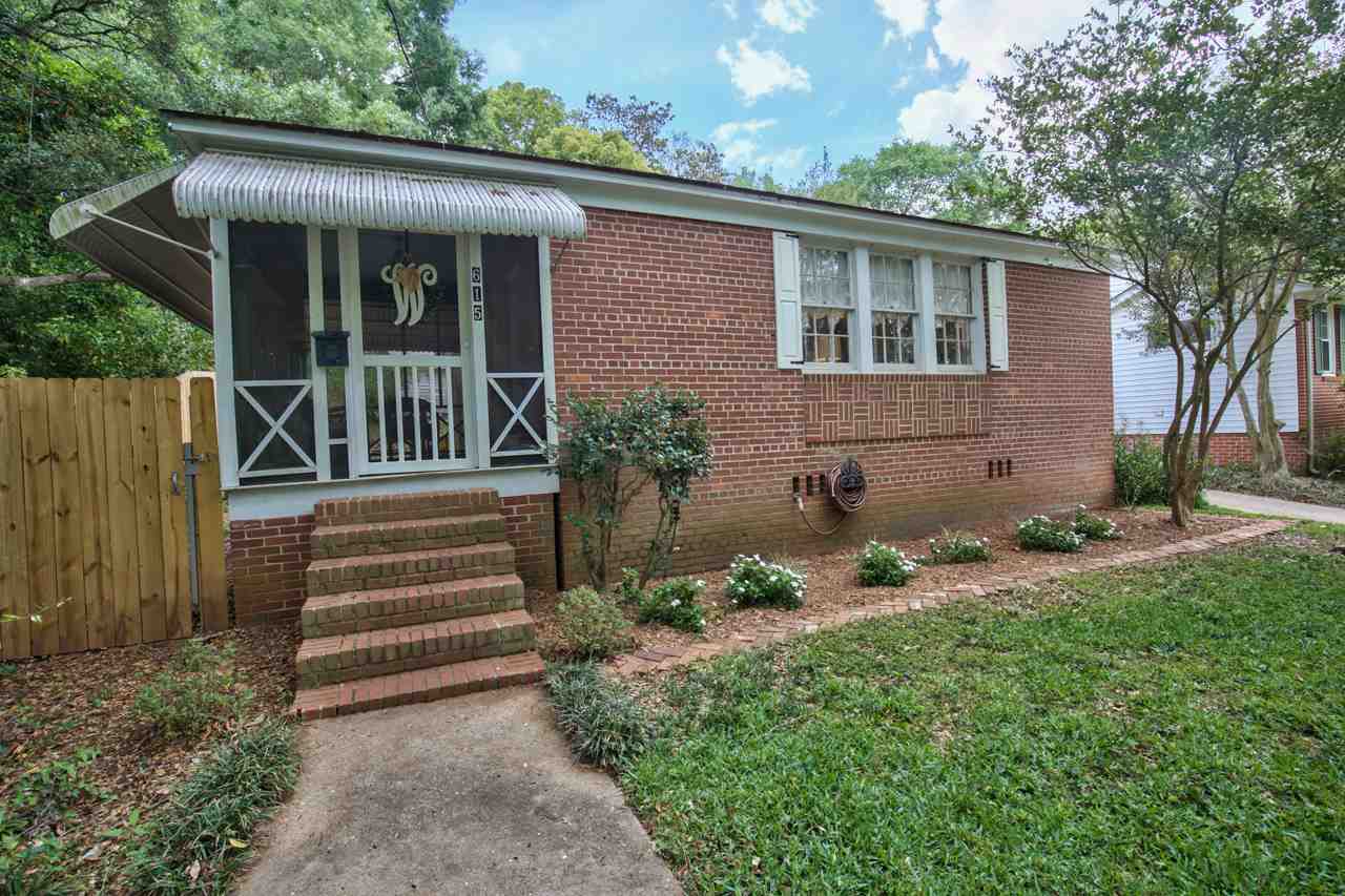 A brick home featuring a welcoming front porch and a well-maintained yard.