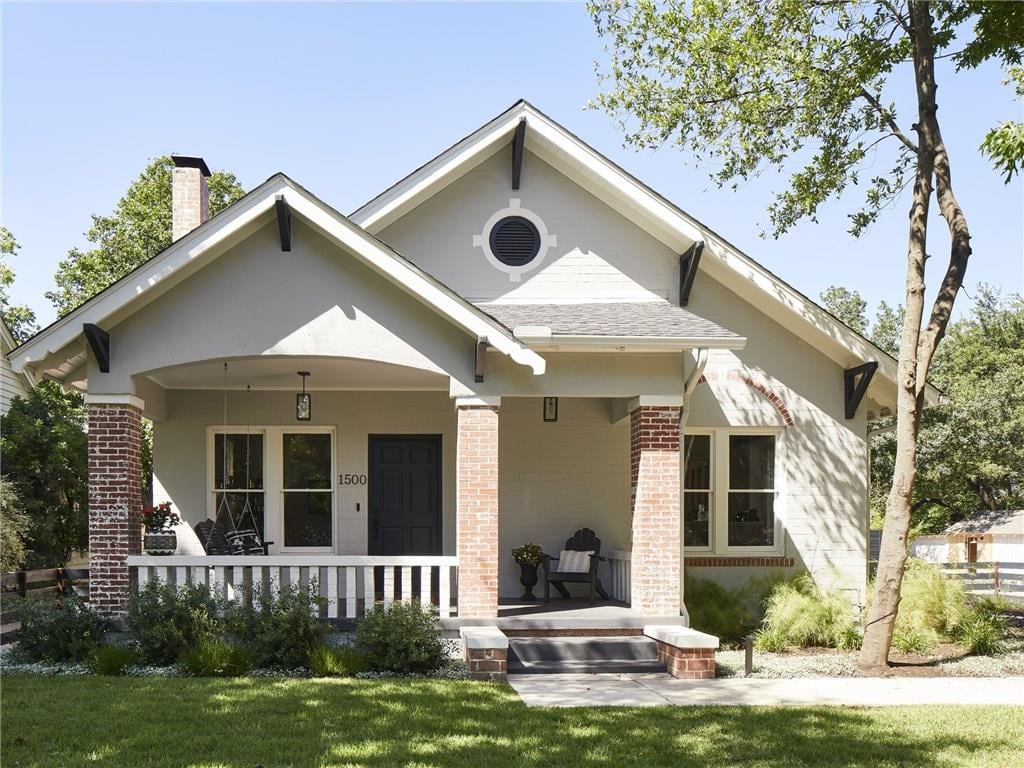 Craftsman-style front porch of a 1932 Pemberton Heights home on Northwood Road in Austin, Texas, showing brick porch columns, exposed rafter tails, and a gabled roofline. Architectural renovation by McWalters Collaborative.