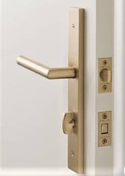 Brass lever handle and lock on a white door.