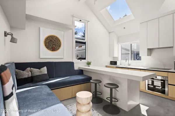 Modern kitchen with a dark blue banquette, breakfast peninsula, white cabinets, and skylight.