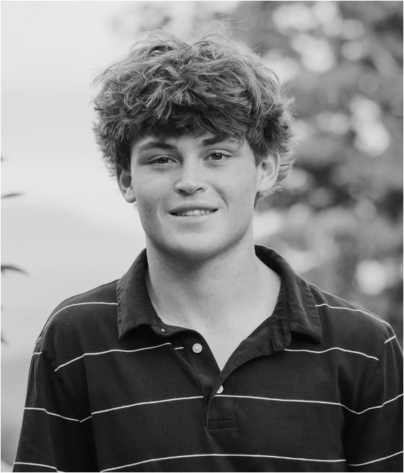 Jack O'Connell in a dark striped polo shirt, photographed outdoors in black and white.