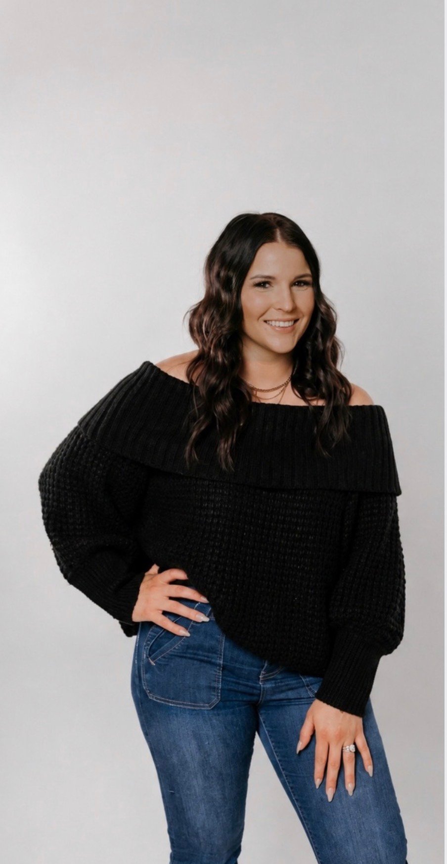 Sydnie Cavegn smiling in a black sweater and blue jeans.
