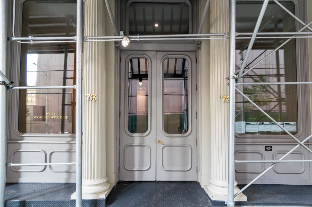 Entrance at 73 Worth Street with gray double doors, fluted columns, and scaffolding.