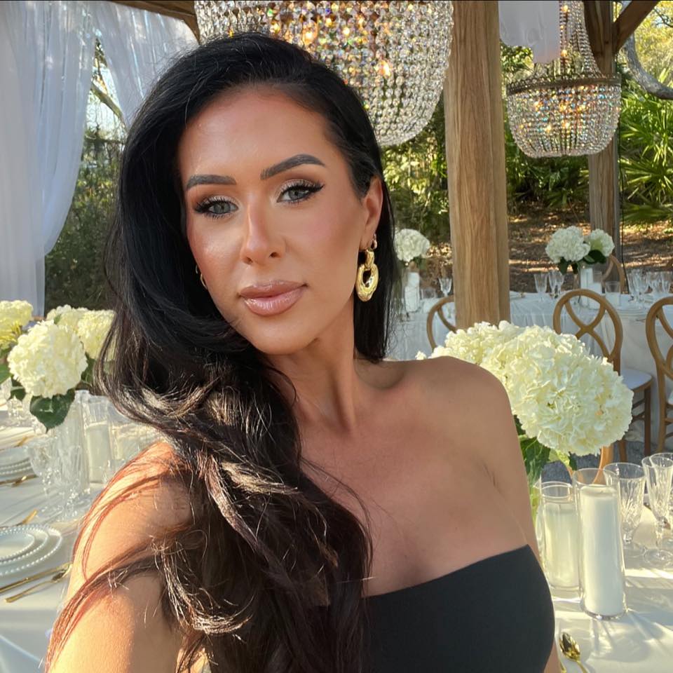 Alexis Stout at an outdoor dining table beneath crystal chandeliers.