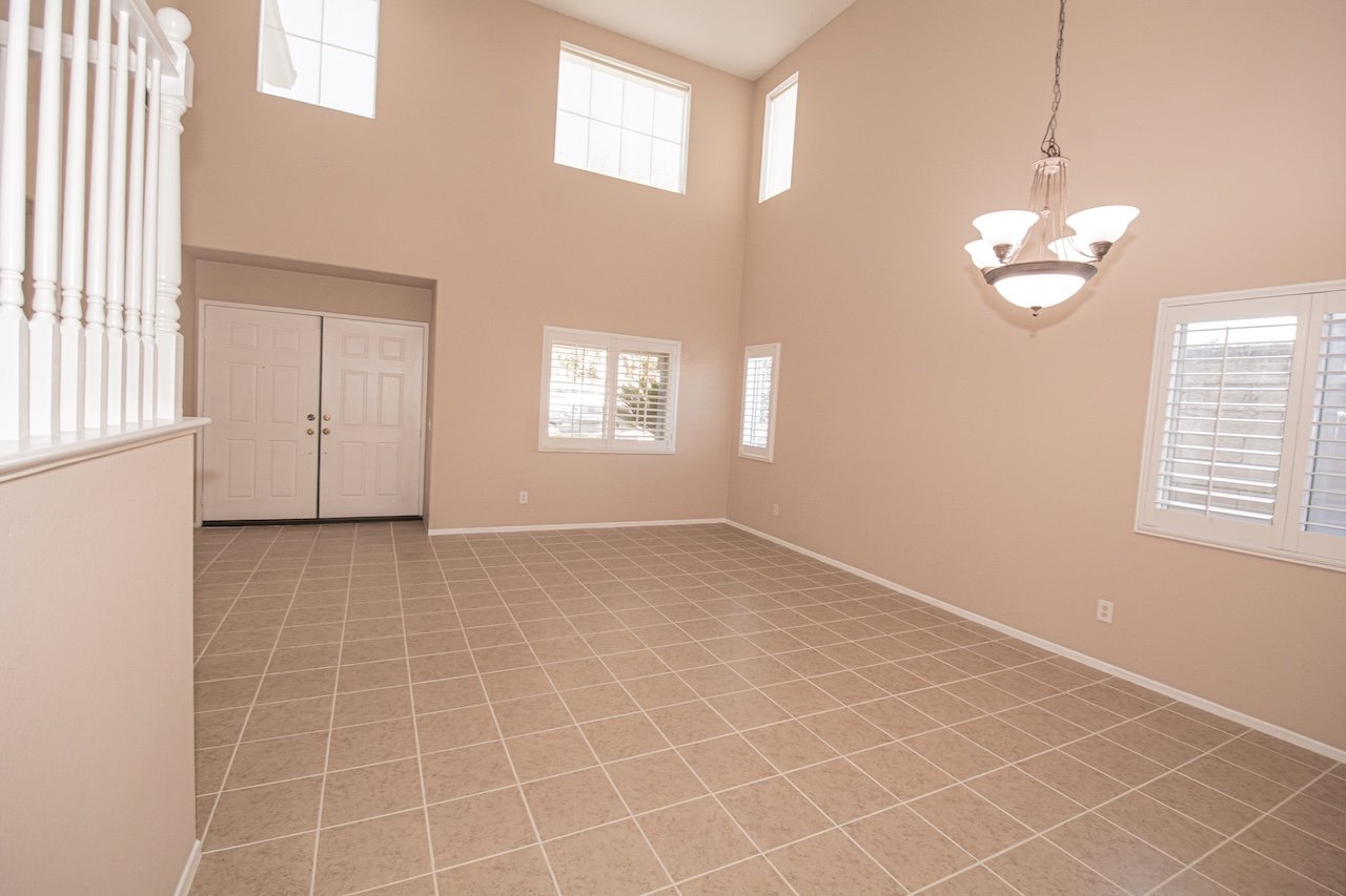 Spacious tiled entry with double front doors, shuttered windows, and a high ceiling.