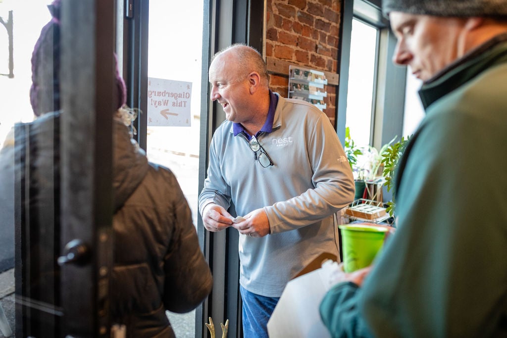 Nest Realty agent talking with visitors at the entrance of a brick-walled office.